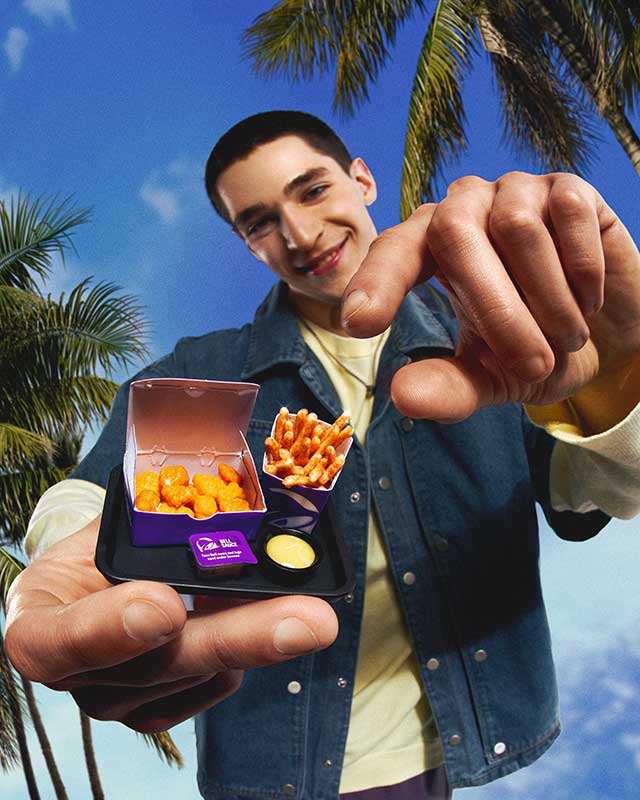 Person holding Miniverse Taco Bell  with palm trees and blue sky in the background