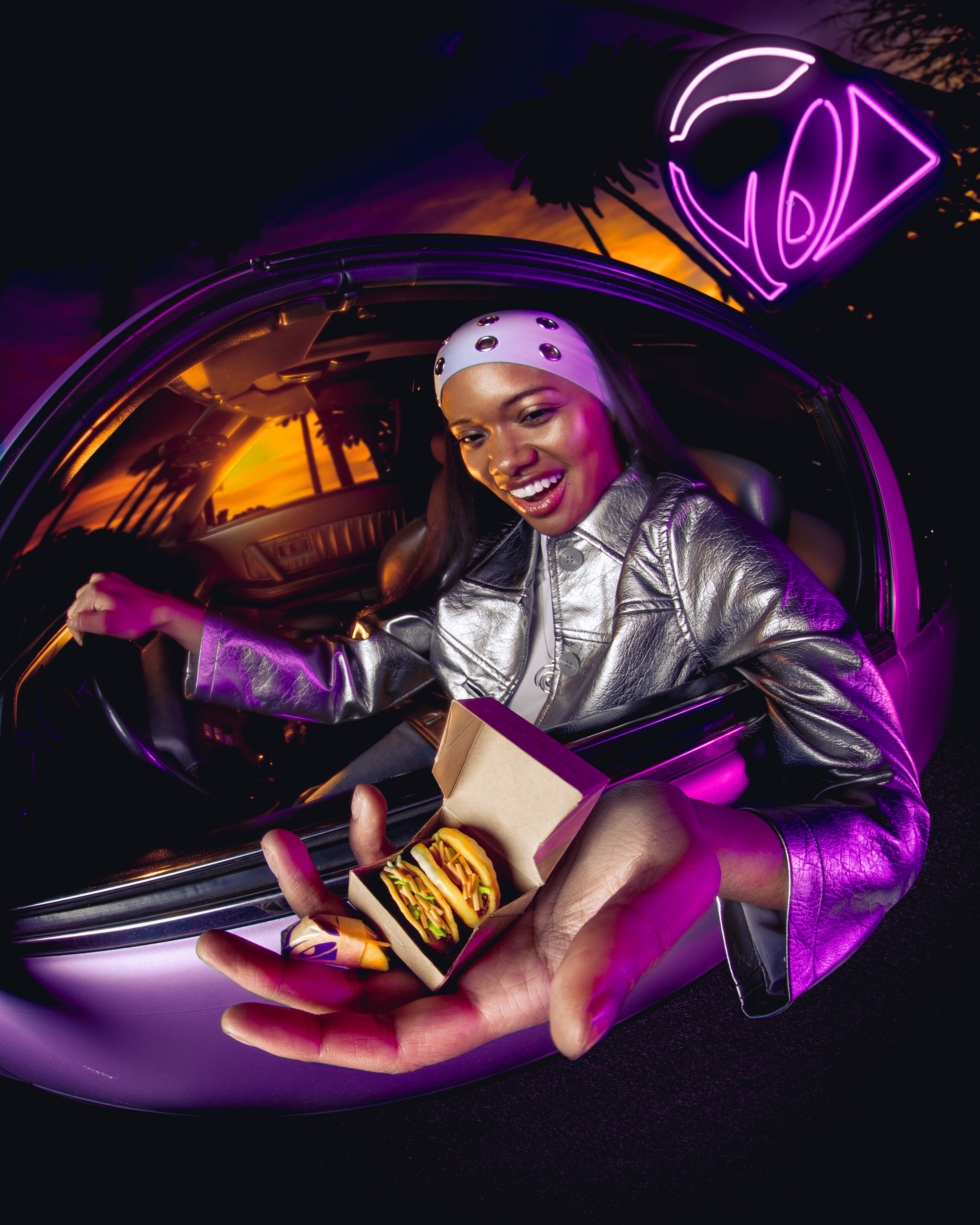 Person in a car holding Miniverse Taco bell tacos with a neon sign in the background