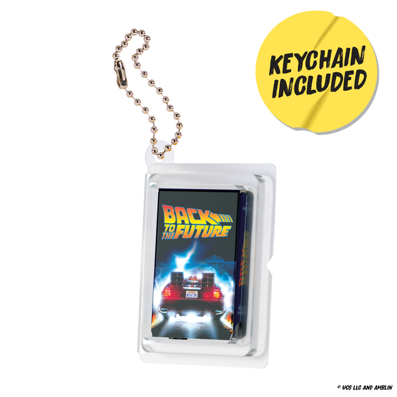 A Back to the Future keychain in a clear plastic case with a ball chain, featuring the DeLorean car graphic and the 'Back to the Future' logo. A yellow circular badge in the top right reads 'KEYCHAIN INCLUDED'.